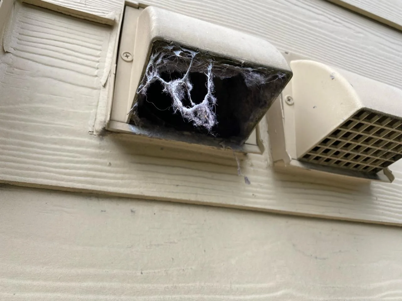 Clogged dryer vent at Beaverton apartment complex — heavy lint accumulation visible at connection point